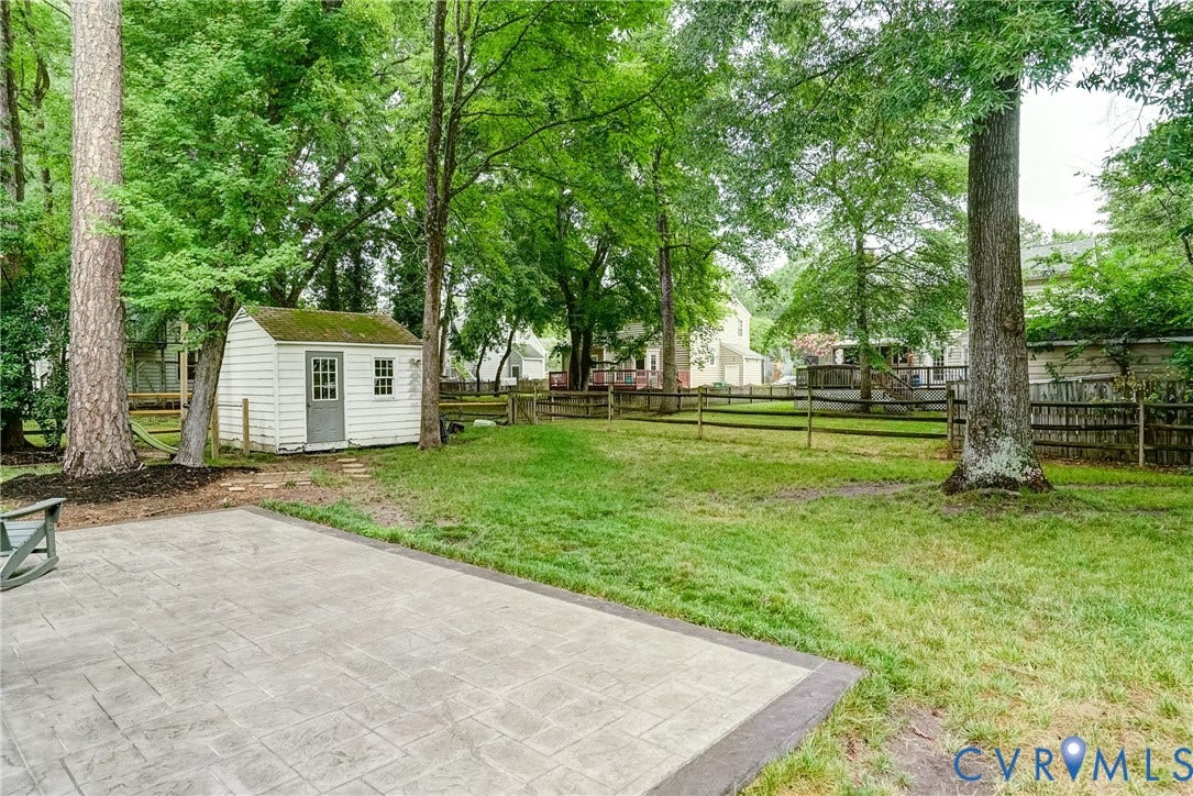 9724 Kingscroft Drive, Kingston, Glen Allen, VA 23060 Expansive backyard featuring a stamped concrete patio, mature trees, a storage shed with paneled siding and double-hung windows, and a wood split-rail fence