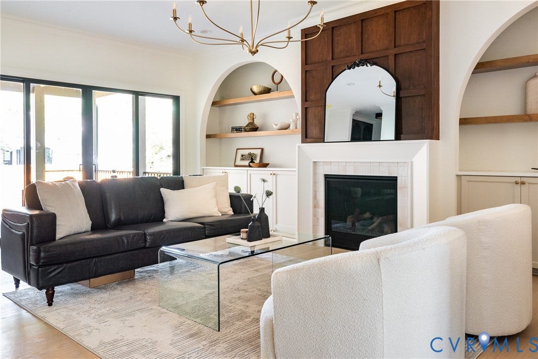 4507 Leonard Parkway, Richmond, VA 23221 Living area featuring light wood-finish flooring, a fireplace with a white surround and dark wood paneling, built-in shelving with arched alcoves, and large glass paneled doors