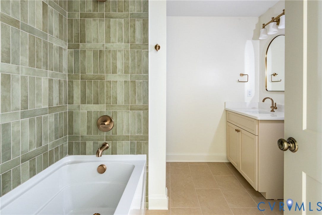 4507 Leonard Parkway, Richmond, VA 23221 Bathroom featuring a white bathtub, vertical tile surround in muted green tones, and bronze-finish fixtures