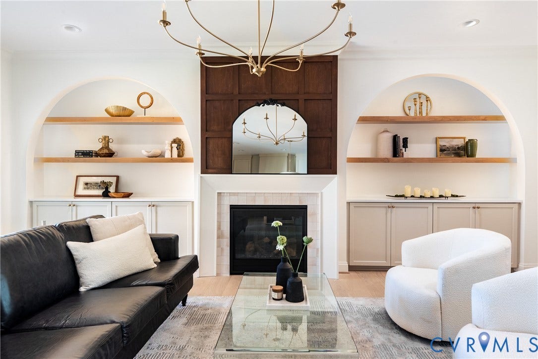 4507 Leonard Parkway, Richmond, VA 23221 Living area featuring a central fireplace with a stone surround and wood paneling, flanked by arched built-in shelving with integrated lighting and base cabinetry
