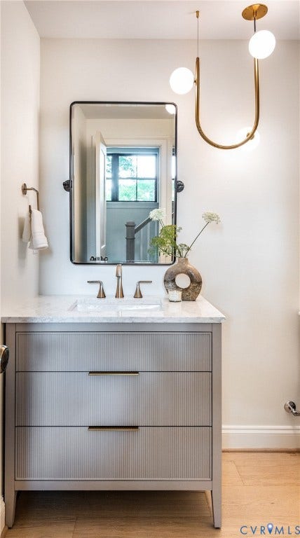 4507 Leonard Parkway, Richmond, VA 23221 Vanity with a light-toned reeded finish, bronze hardware, and a stone countertop with an undermount sink