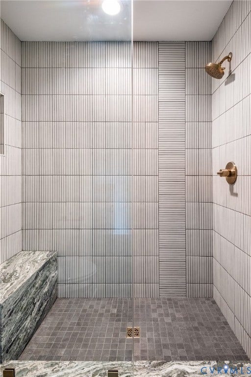 4507 Leonard Parkway, Richmond, VA 23221 Spacious shower enclosure with vertical fluted wall tiles, an integrated natural stone bench, square mosaic floor tiles, a glass panel, and brass shower fixtures