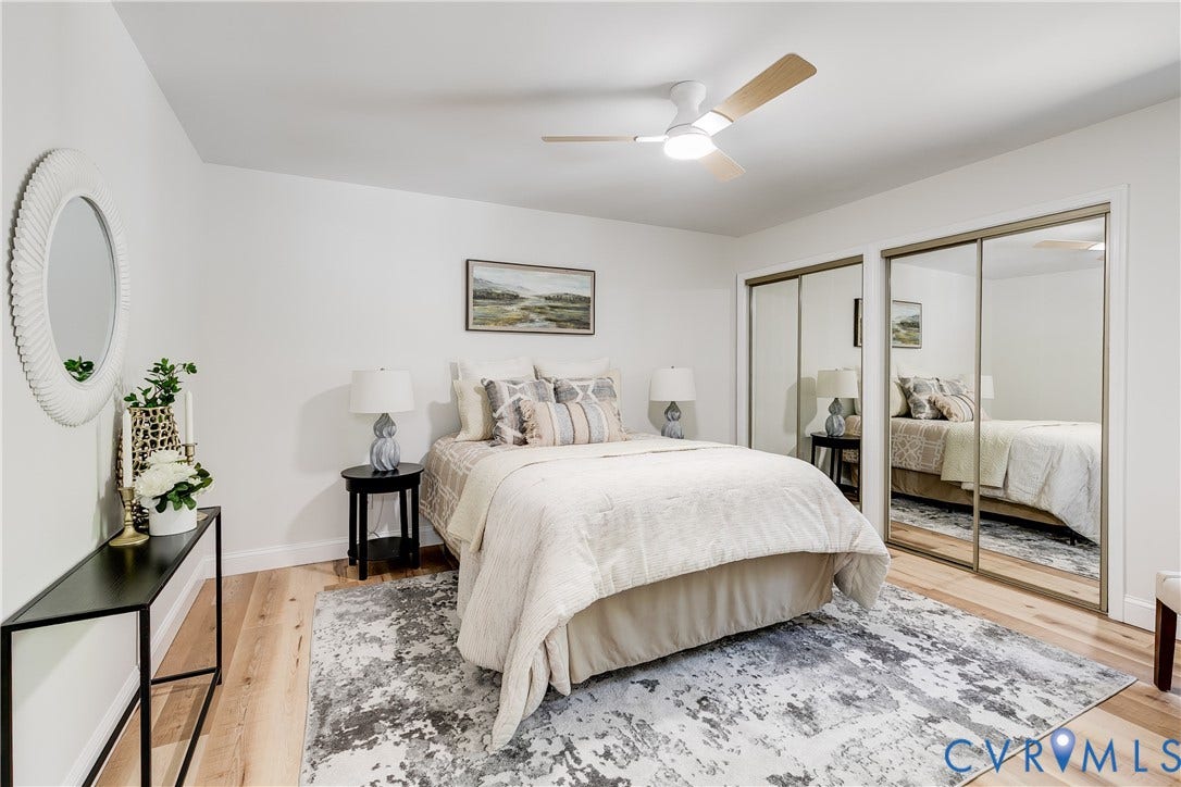 Comfortable primary bedroom with updated flooring, new ceiling fan, and mirrored sliding door closets