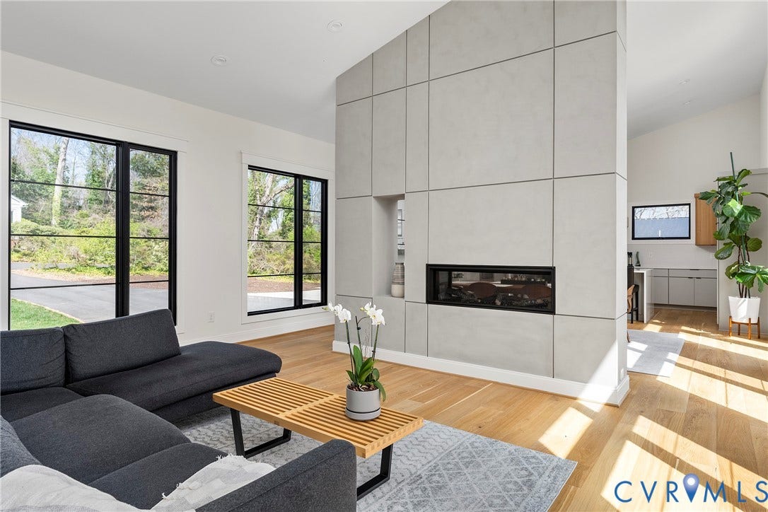 7301 Riverside Drive, Richmond, VA 23225 Spacious living area featuring a linear fireplace within a paneled wall, wood-finish flooring, high ceilings, and black-framed windows
