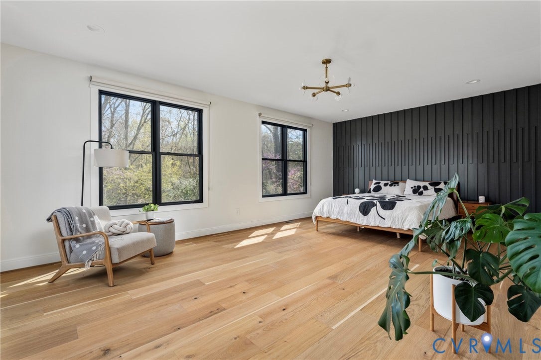 7301 Riverside Drive, Richmond, VA 23225 Spacious room featuring wide plank wood-finish flooring, a striking black accent wall, and two large windows with black frames