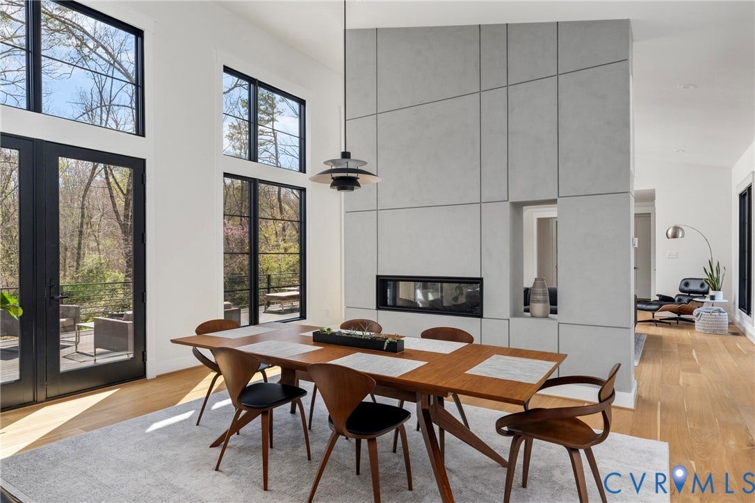 7301 Riverside Drive, Richmond, VA 23225 Dining area featuring a built-in fireplace with a contemporary surround, expansive glass doors, multiple large windows with dark frames, wood-finish flooring, and a modern pendant light fixture