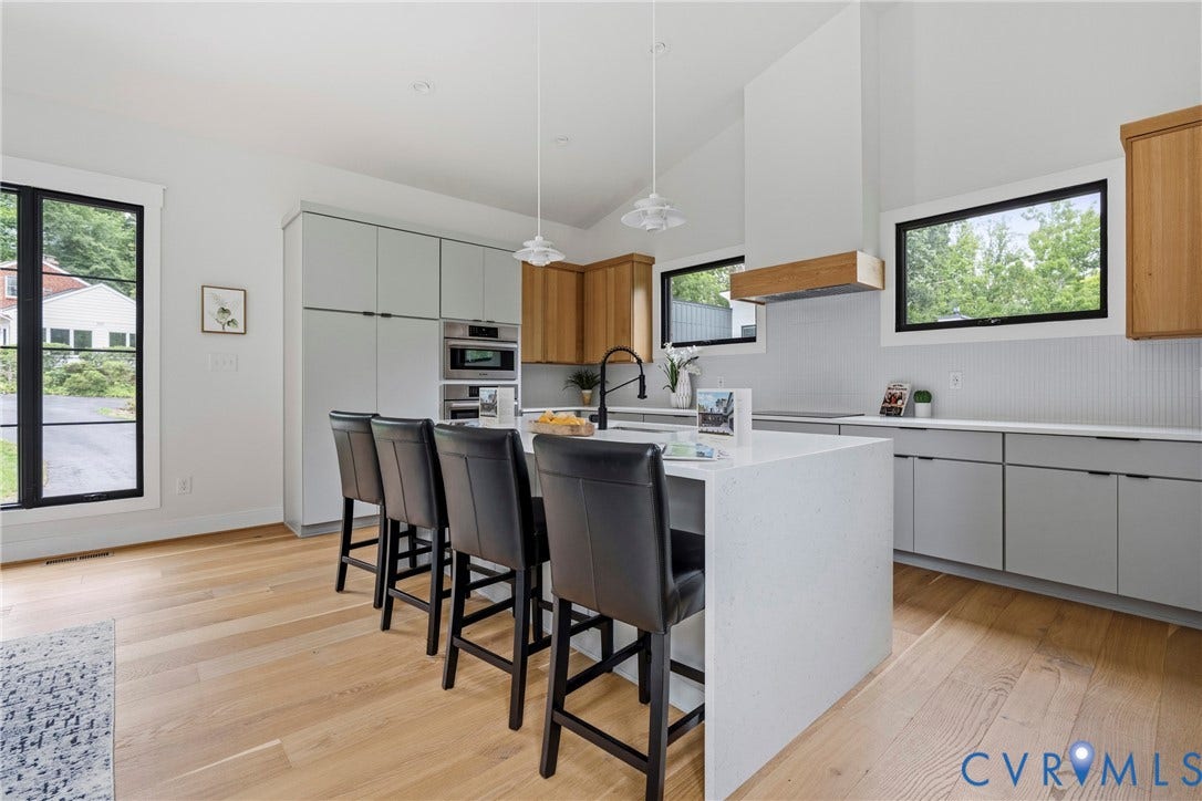 7301 Riverside Drive, Richmond, VA 23225 Modern kitchen featuring a large center island with seating, integrated appliances, natural wood-finish flooring, and light gray cabinetry