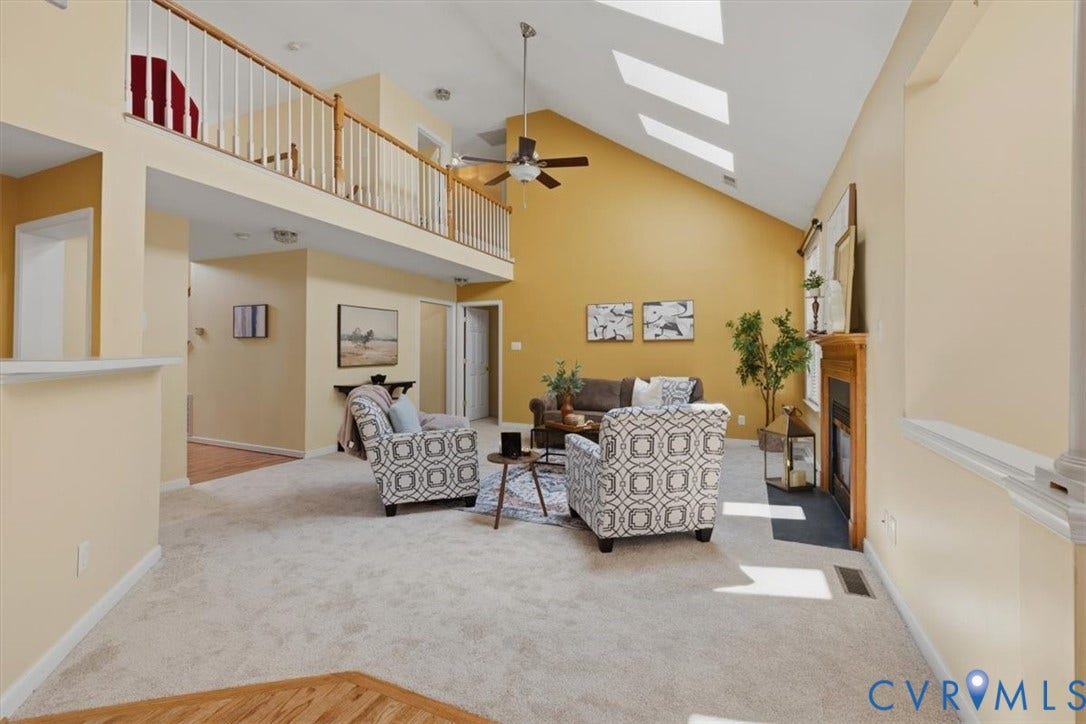 1824 Sidney Court, Glen Allen, VA 23059 Living area featuring vaulted ceilings, skylights, a gas fireplace with a wood-finish mantel, an overhead ceiling fan, and an upper-level balcony