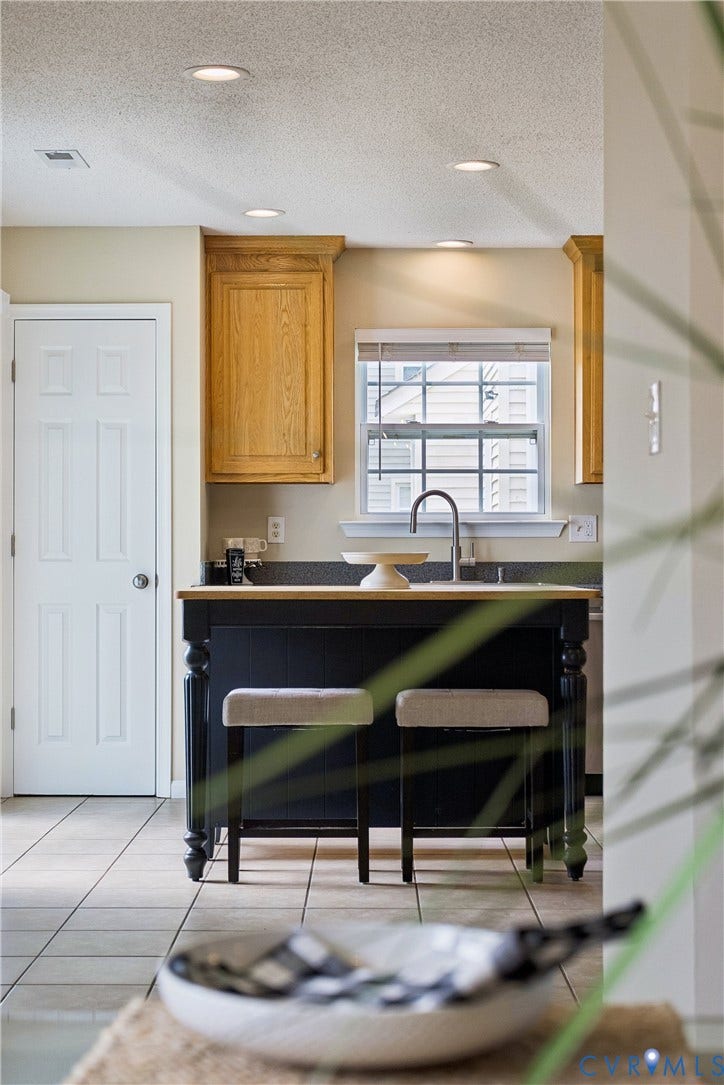 21 St Johns Drive, Hampton, VA 23666 Kitchen island featuring a wood-finish countertop and dark cabinetry with turned legs