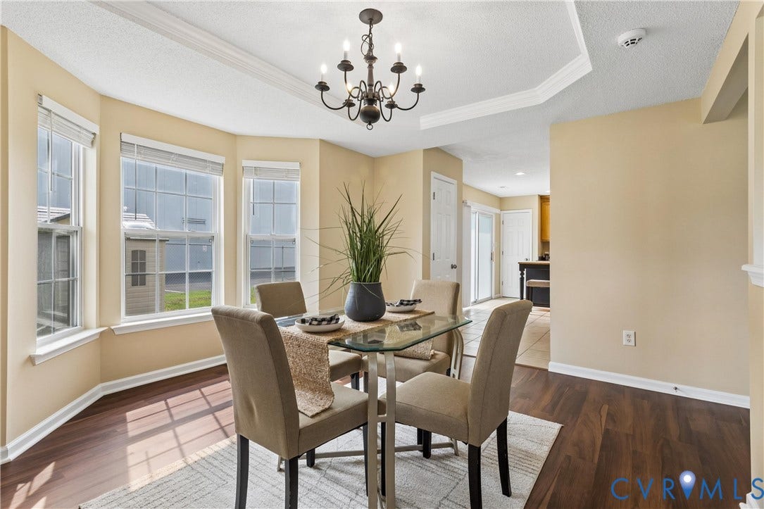 21 St Johns Drive, Hampton, VA 23666 Dining area featuring a bay window with multiple panes, wood-finish flooring, a tray ceiling detail, and an overhead chandelier