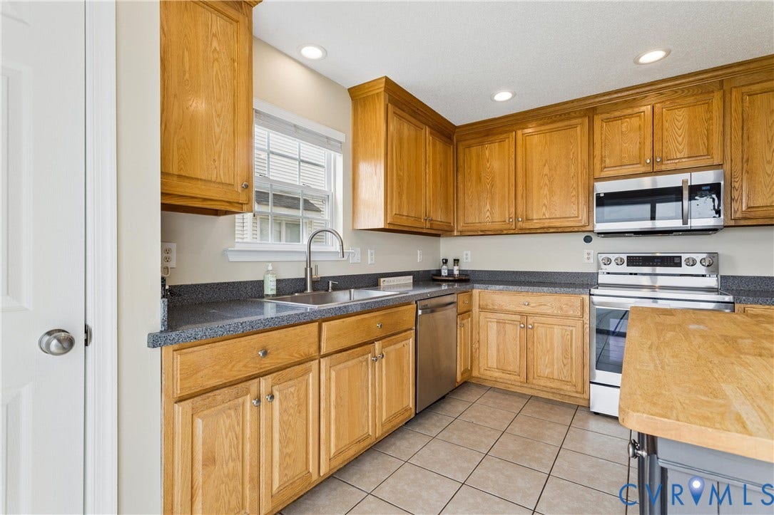 21 St Johns Drive, Hampton, VA 23666 Kitchen featuring extensive wood cabinetry, stainless steel appliances, a stainless steel sink with a gooseneck faucet, dark countertops, and square tile flooring