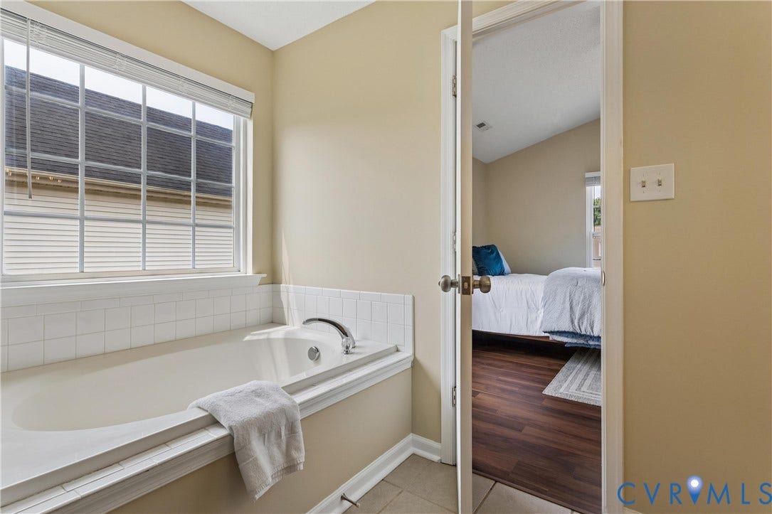 21 St Johns Drive, Hampton, VA 23666 Built-in soaking tub with chrome fixtures, set against a tiled surround and a large window with horizontal blinds