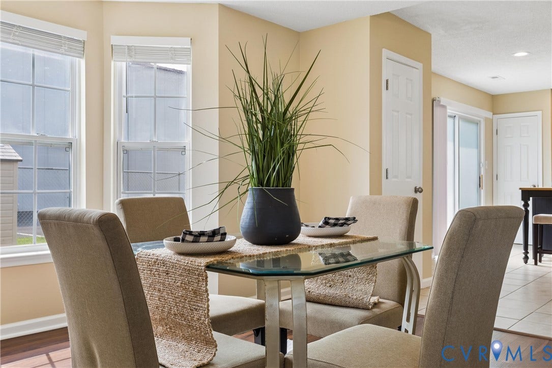 21 St Johns Drive, Hampton, VA 23666 Dining area featuring a glass-top table, hard-surface flooring, multiple windows with blinds, and a paneled door