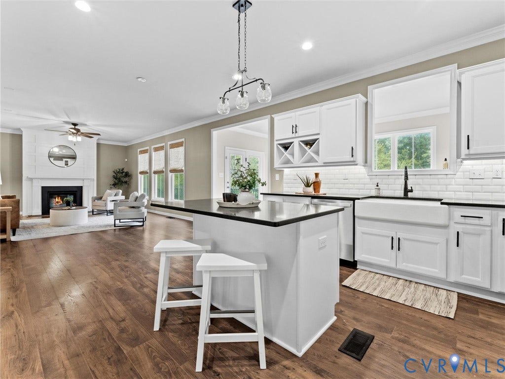 16701 Laurel Park Drive, Moseley, VA 23120 Contemporary kitchen featuring an island with seating, white shaker-style cabinetry, a white farmhouse sink, subway tile backsplash, and dark countertops