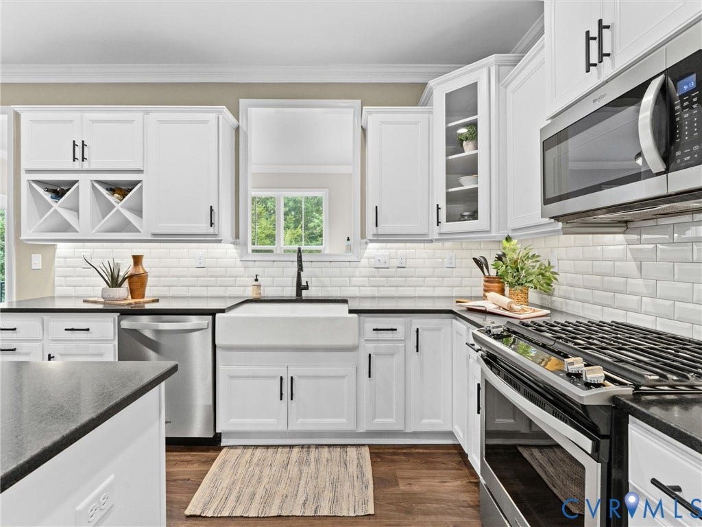 16701 Laurel Park Drive, Moseley, VA 23120 Bright kitchen featuring white shaker cabinetry, black countertops, stainless steel appliances, a farmhouse sink, and subway tile backsplash