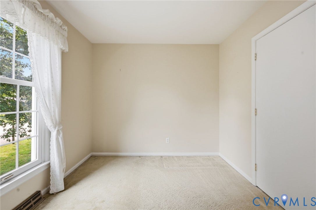 121 Huntington Road, Colonial Heights, VA 23834 Neutral-toned room featuring a large window with gridded panes, light-colored carpeting, and a white interior door