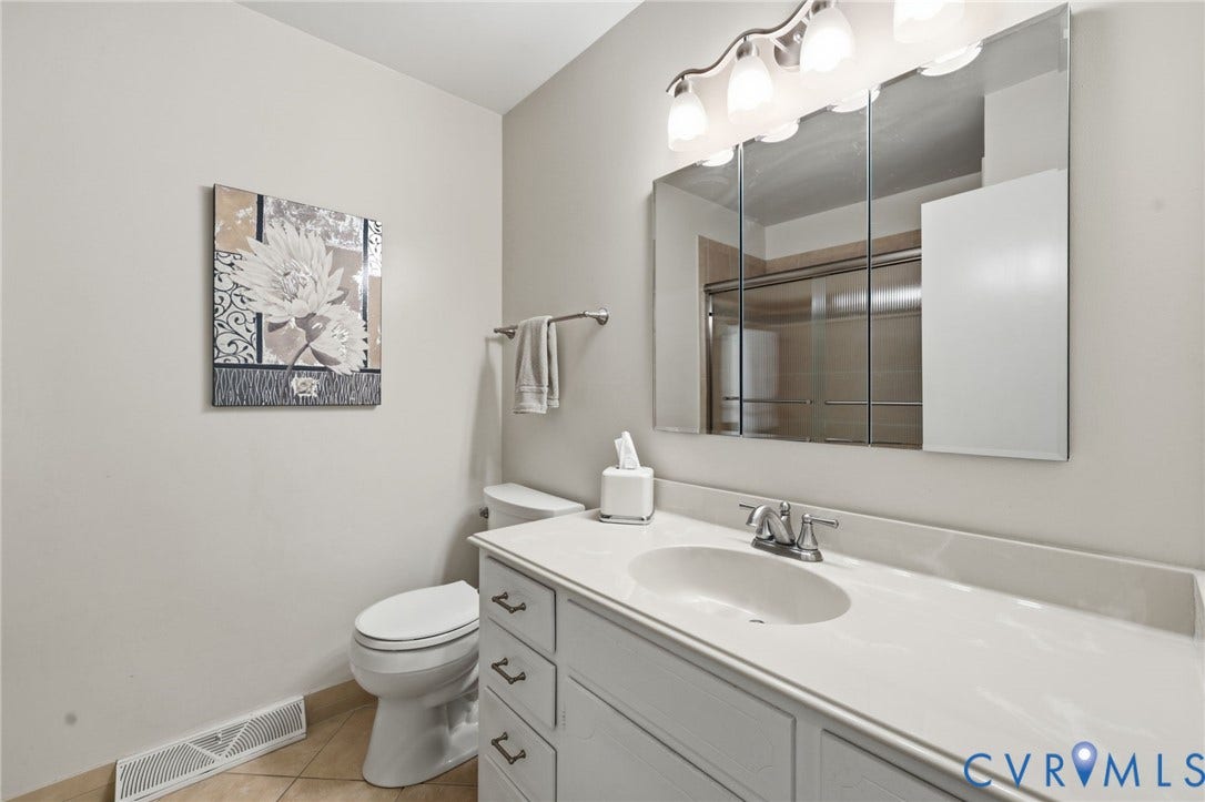 121 Huntington Road, Colonial Heights, VA 23834 Vanity featuring an integrated sink with a two-handle faucet, a white countertop, and white cabinetry with dark pulls
