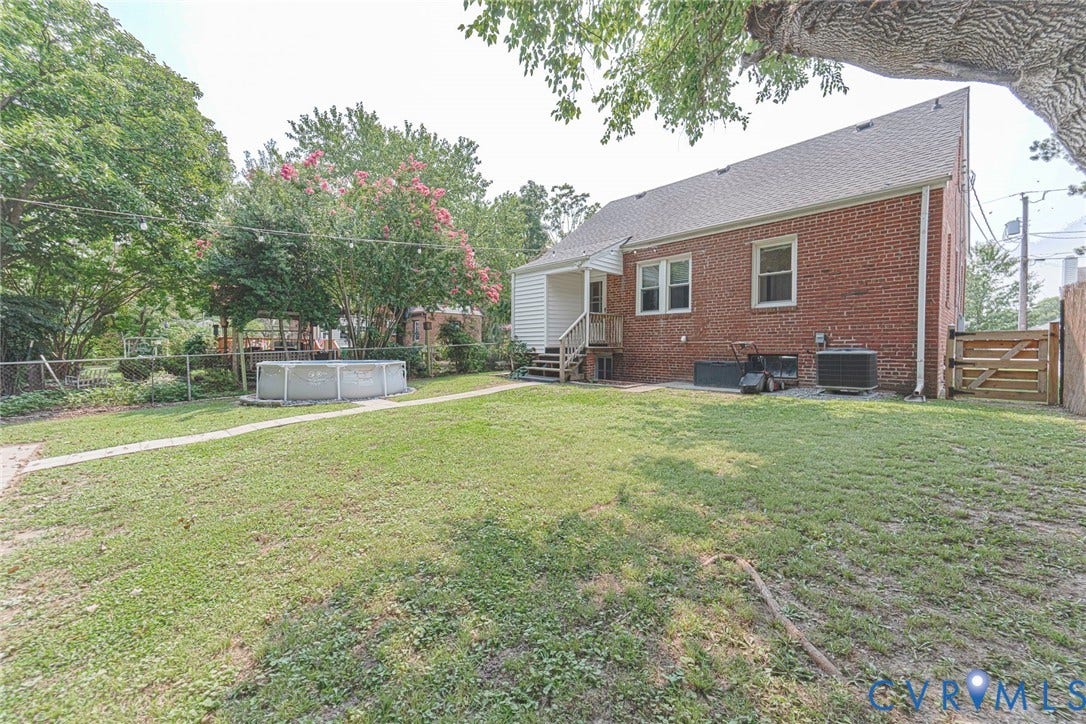 1402 Rhode Island Avenue, Glen Allen, VA 23060 Expansive backyard featuring a manicured lawn, an above-ground pool, a chain-link fence, mature trees, and a wooden gate