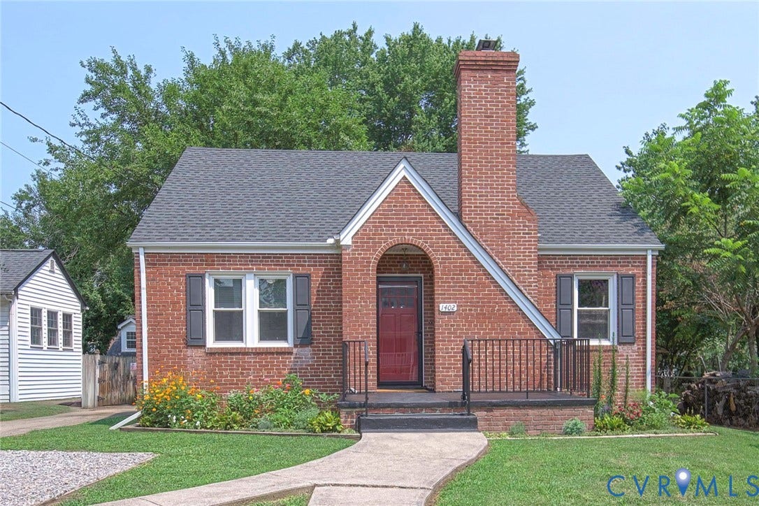 1402 Rhode Island Avenue, Glen Allen, VA 23060 Brick exterior with a prominent chimney, dark gray roof, red entry door, decorative black shutters, and mature front landscaping