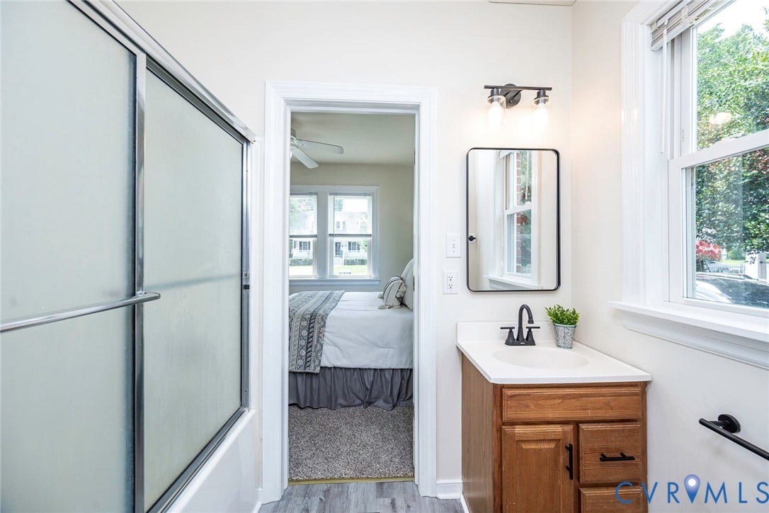 1402 Rhode Island Avenue, Glen Allen, VA 23060 Bathroom featuring a frosted glass shower enclosure, wood-finish vanity with countertop sink, matte black faucet, and a rectangular framed mirror