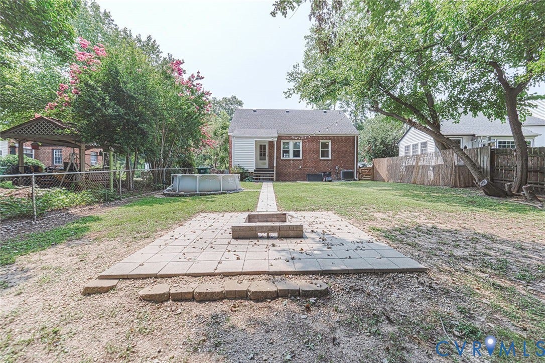 1402 Rhode Island Avenue, Glen Allen, VA 23060 Expansive backyard featuring a brick exterior, a paver patio with a built-in fire pit, mature trees, and a wooden gazebo