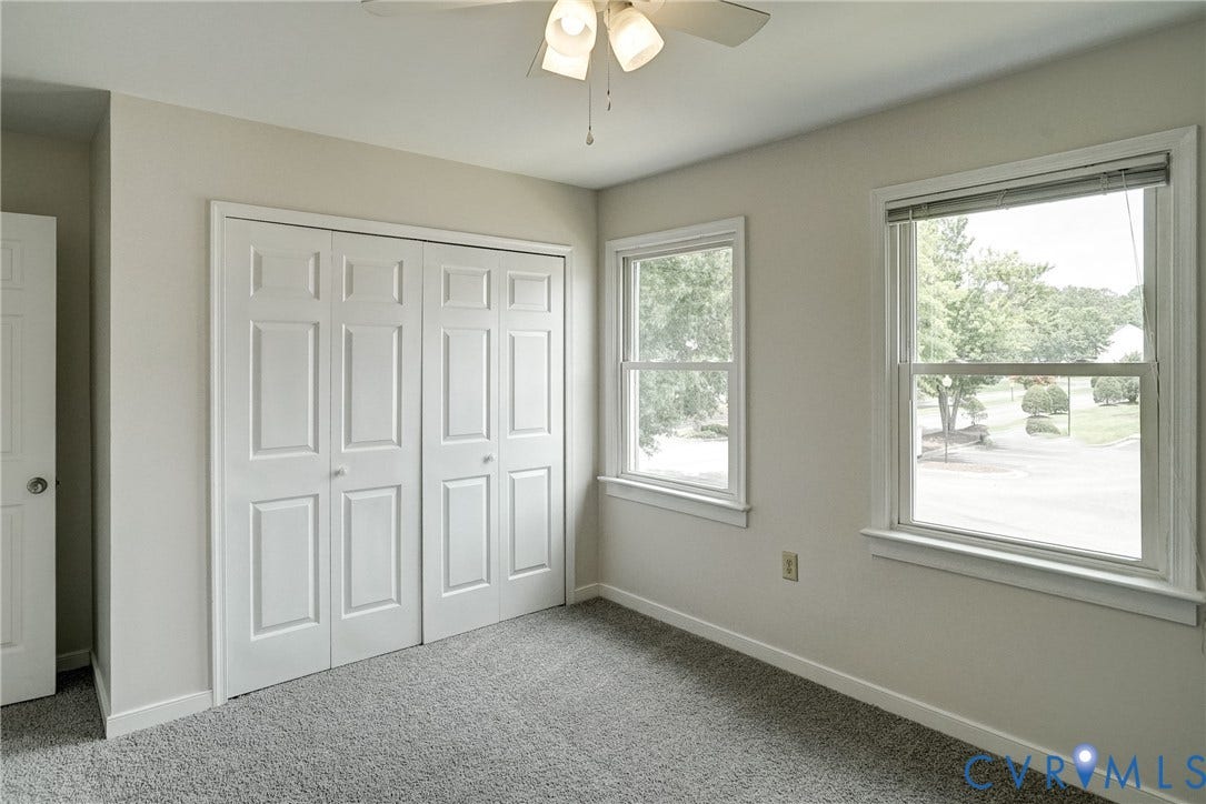 2221 High Bush Circle, Glen Allen, VA 23060 Carpeted room featuring a ceiling fan with light fixture, two double-hung windows, and a bi-fold door closet with paneled doors
