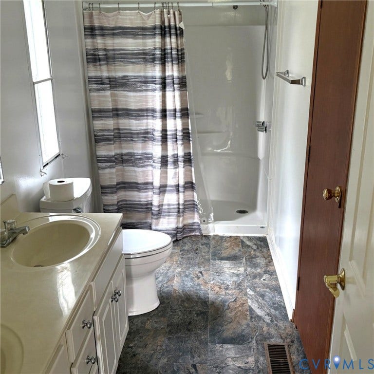 Bathroom featuring a white vanity, and a stand-up shower.
