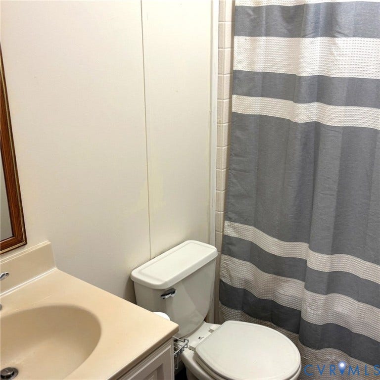 Hall bathroom featuring a neutral-toned vanity with an sink, white toilet, and tub/shower