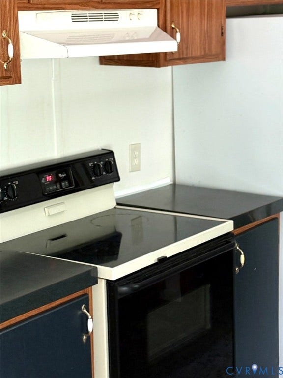 Kitchen area featuring an electric range with a black ceramic cooktop, a white range hood, dark wood-finish upper cabinetry, and dark base cabinetry with a contrasting countertop
