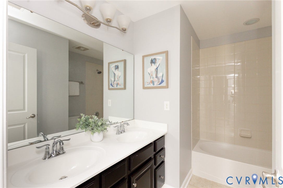 12814 Bailey Hill Court, Bayhill Pointe, Midlothian, VA 23112 Dual vanity with a white countertop and dark cabinetry, large wall-mounted mirror, and a built-in bathtub with tiled surround