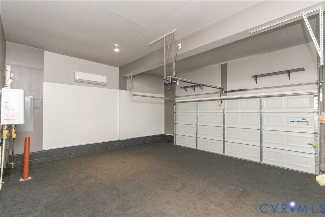 12814 Bailey Hill Court, Bayhill Pointe, Midlothian, VA 23112 Spacious garage with a paneled overhead door, wall-mounted air conditioning unit, and a tankless water heater