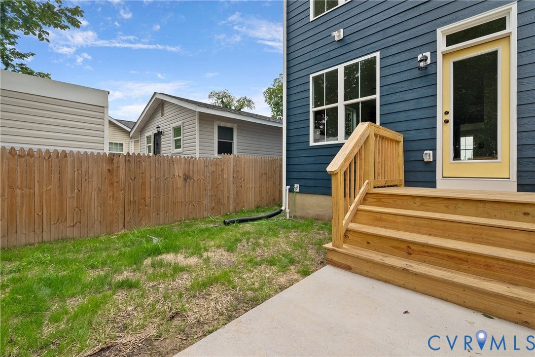 Rear exterior featuring wood-finish siding, a private wood privacy fence, a concrete patio, and a wood deck with stairs