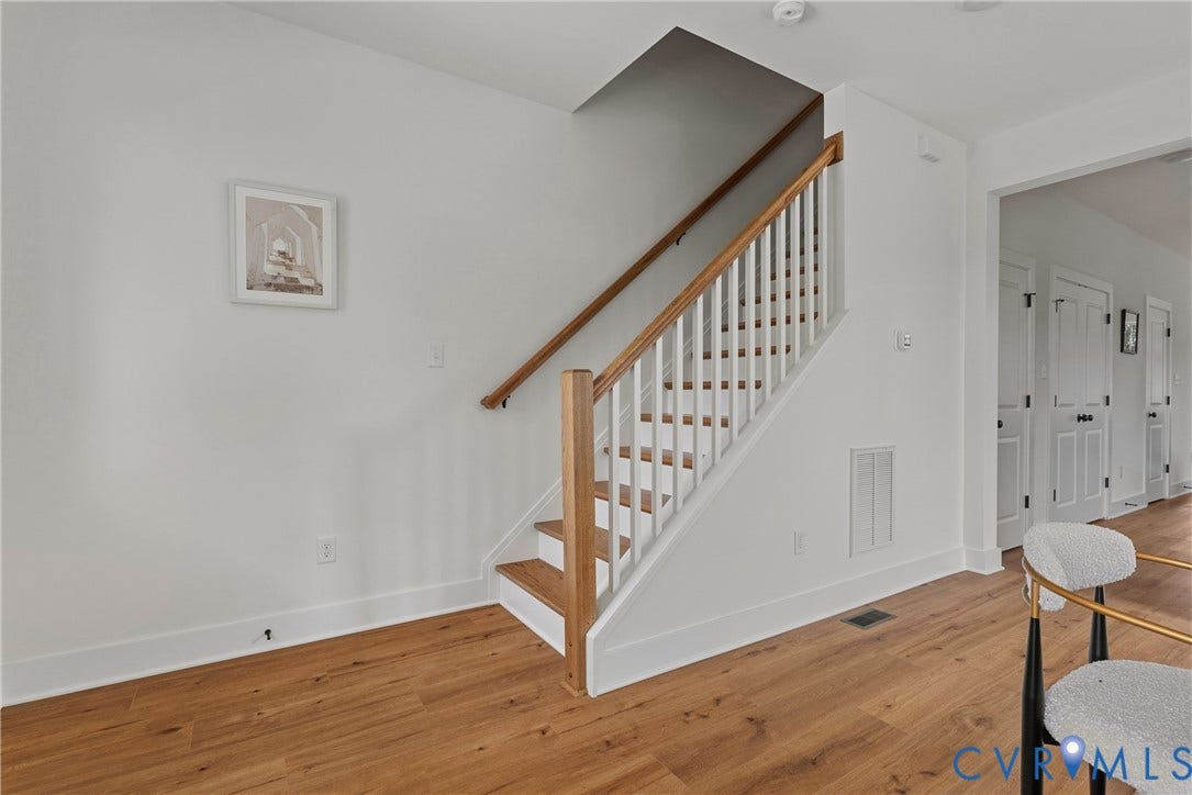 Staircase with wood-finish treads and handrail, white risers, and white balusters