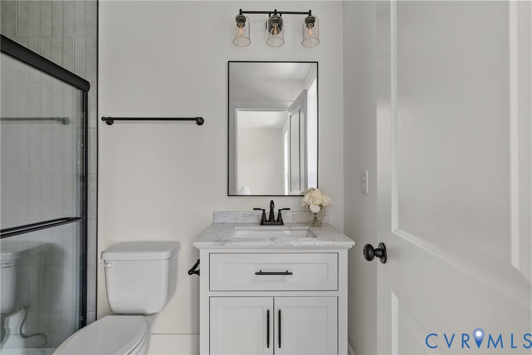 Vanity with a solid surface countertop and undermount sink, framed mirror, and a wall-mounted light fixture