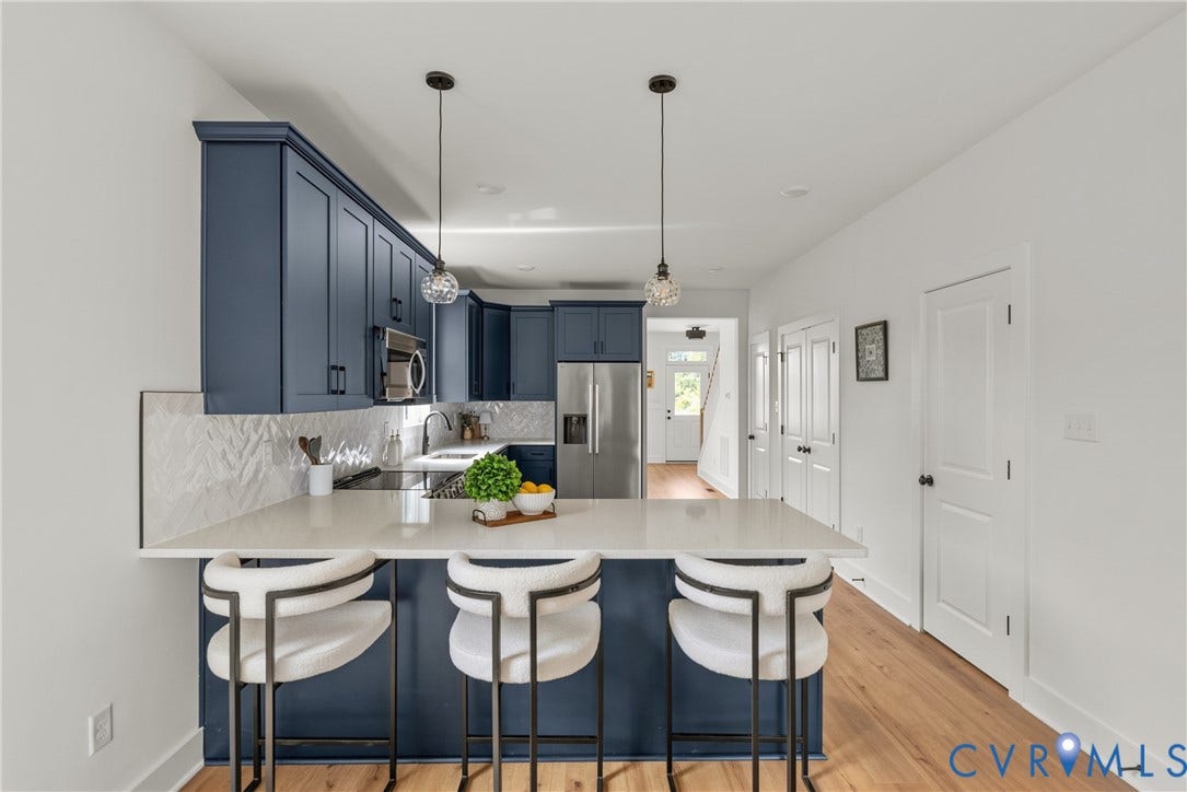 Kitchen featuring blue cabinetry, white countertops, a chevron tile backsplash, stainless steel appliances, and wood-finish flooring