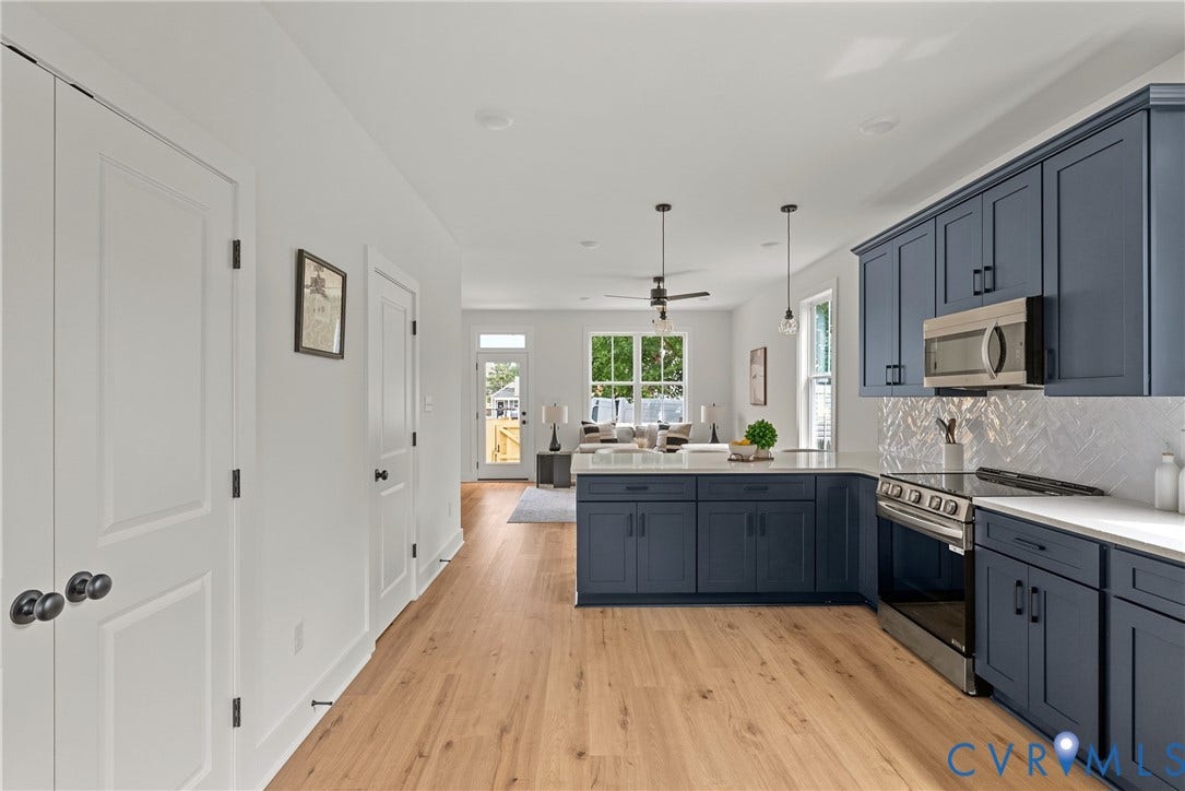 Open concept kitchen featuring blue cabinetry, stainless steel appliances, wood-finish flooring, and white countertops