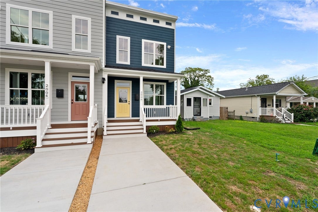 Two-story exterior with horizontal siding and contrasting trim, featuring a covered front porch with white railings, and a solid wood entry door with glass panel