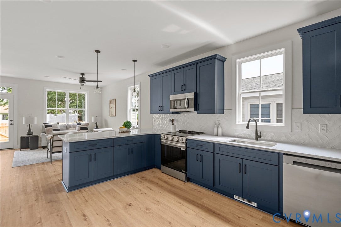 Open-concept kitchen featuring blue cabinetry, white countertops, stainless steel appliances, and wood-finish flooring