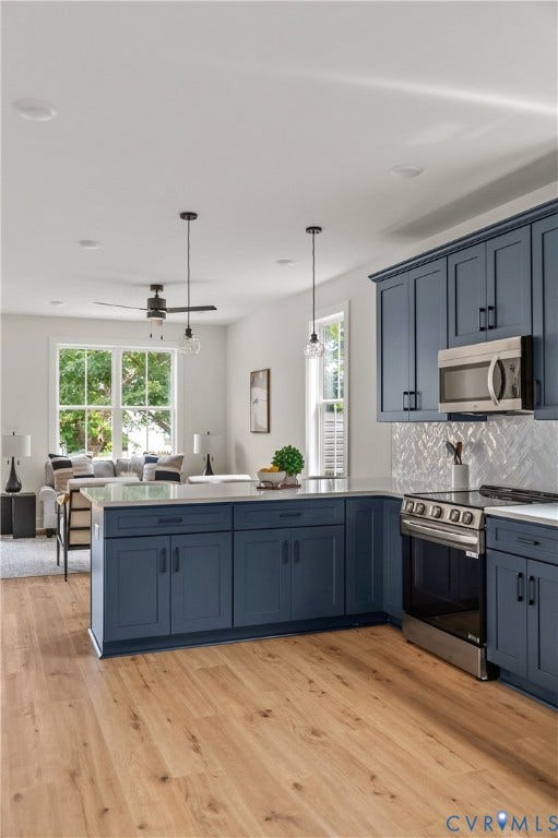 Kitchen featuring dark blue cabinetry, stainless steel appliances, a white tile backsplash, and light wood-finish flooring