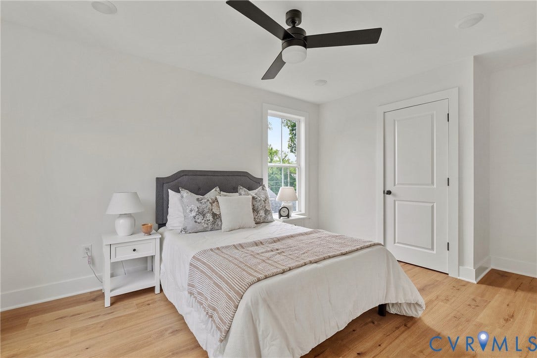 Bright room featuring wood-finish flooring, a window with exterior views, a ceiling fan, a white paneled door, and recessed lighting
