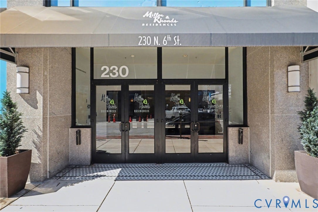 230 N 6th Street, #U325, Richmond, VA 23219 Building entrance featuring a contemporary awning, stone facade, glass double doors, and integrated outdoor lighting fixtures