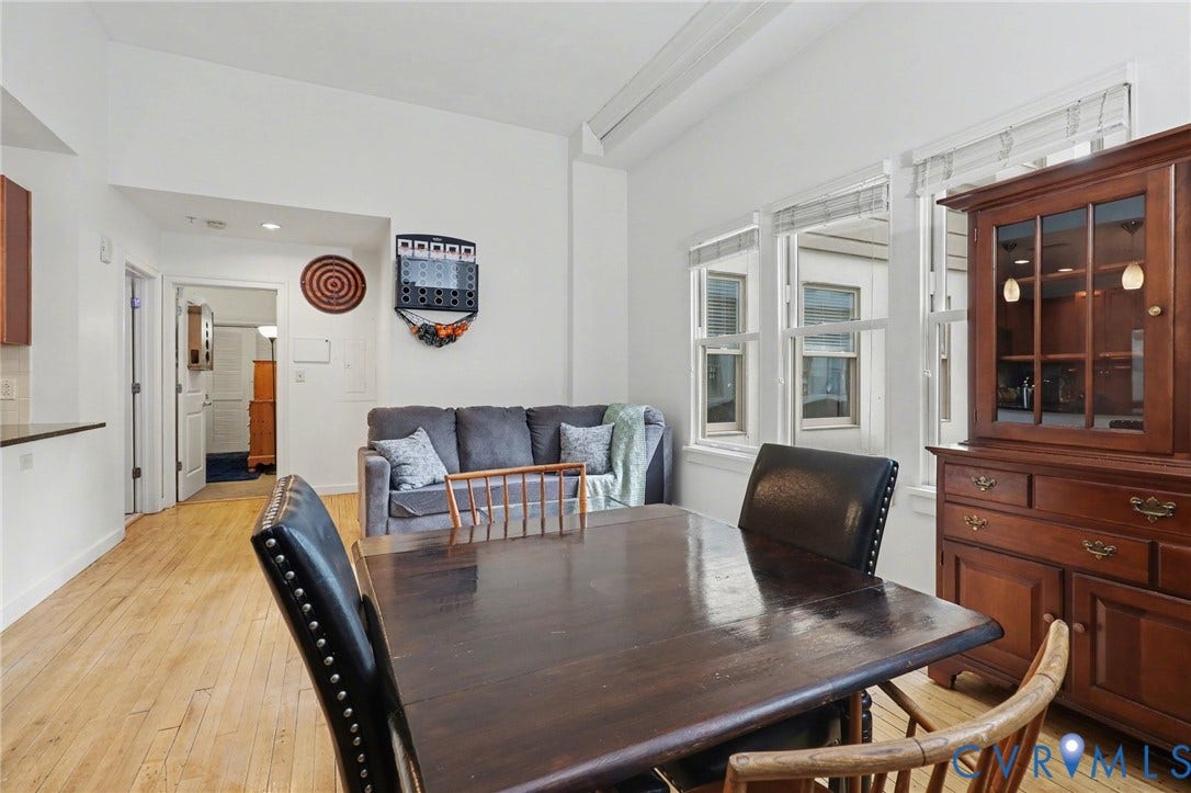 230 N 6th Street, #U325, Richmond, VA 23219 Open-concept living space featuring light wood-finish flooring, white walls, multiple windows with blinds, and a built-in kitchen counter with dark surfacing
