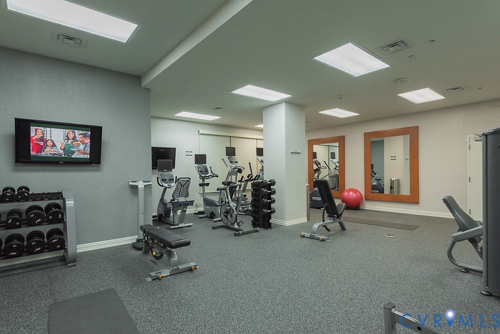 230 N 6th Street, #U325, Richmond, VA 23219 Fitness center featuring durable rubber flooring, recessed ceiling lighting, wall-mounted television, and mirrored wall accents
