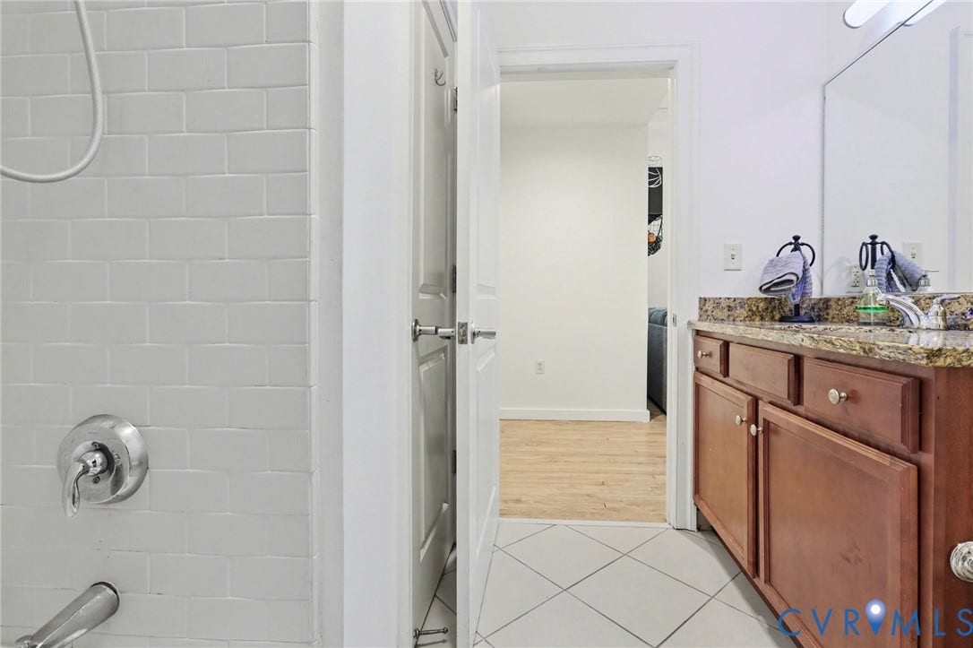 230 N 6th Street, #U325, Richmond, VA 23219 Bathroom featuring a subway-tiled shower with chrome fixtures, a wood-finish vanity with drawer and cabinet storage, a speckled stone countertop, and an integrated sink