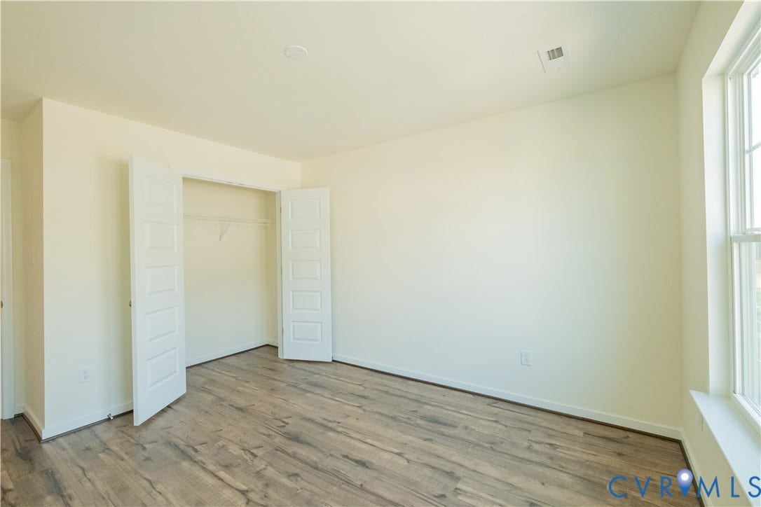 18429 Palisades Court, Chesterfield, VA 23120 Spacious room featuring wood-finish flooring, light-toned walls, a large window, a bi-fold closet with wire shelving, and a ceiling light fixture