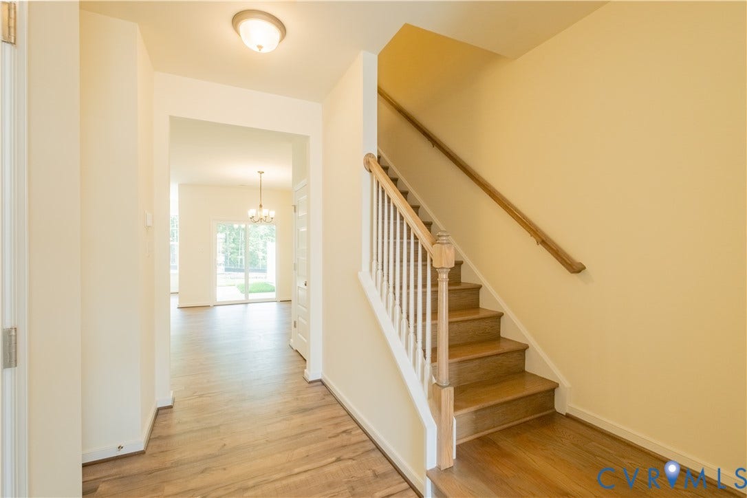 18429 Palisades Court, Chesterfield, VA 23120 Foyer featuring wood-finish flooring, a built-in staircase with wood treads and white balusters, an arched doorway, and an overhead flush-mount light fixture