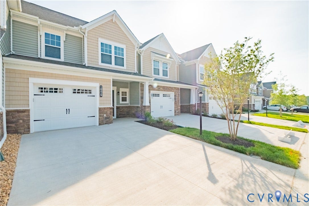 18429 Palisades Court, Chesterfield, VA 23120 Contemporary townhome-style exterior featuring a two-car garage with decorative hardware, mixed siding, stone veneer accents, concrete driveway, and mature landscaping