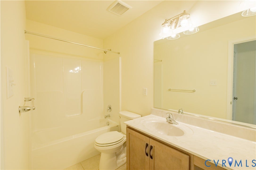 18429 Palisades Court, Chesterfield, VA 23120 Bathroom featuring a white tub and shower combination, light wood-finish vanity with a white countertop and integrated sink, and an expansive wall-mounted mirror