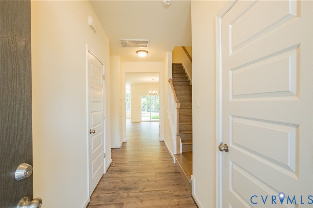 18429 Palisades Court, Chesterfield, VA 23120 Entryway featuring wood-finish flooring extending into the main living spaces, crisp white paneled doors, a carpeted staircase with wood handrails, and an overhead flush mount light fixture