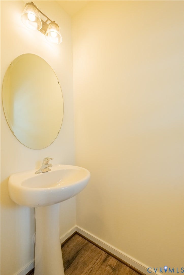 18429 Palisades Court, Chesterfield, VA 23120 Pedestal sink with chrome faucet, complemented by an oval mirror and two-light vanity fixture